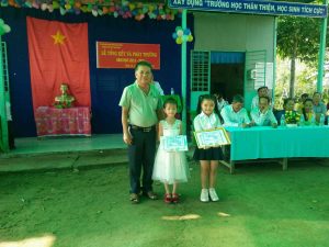 Ông Lâm Sơn Thì đại diện CMHS phát thưởng cho 2 em học sinh đạt thành tích trong các cuộc thi phong trào